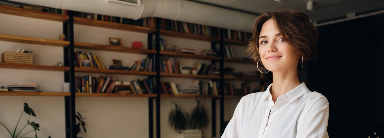 Jonge vrouwelijke ondernemer met een bureau op de achtergrond