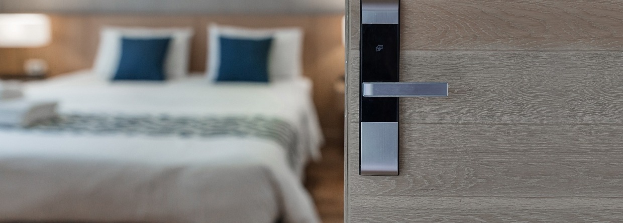 Open deur slaapkamer van vakantieverblijf met een bed op de achtergrond
